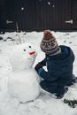 Outdoor games in winter. Child cute caucasian boy six years old in the snow sculpts a snowman. Winter games, winter time