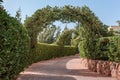 Outdoor Green secret garden with arched entry and gate. Tiled park path in a tunnel under an arch entwined with tropical
