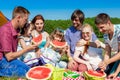 Outdoor group portrait of happy company having picnic on green grass in park and enjoying watermelon Royalty Free Stock Photo