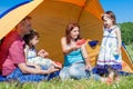 Outdoor group portrait of happy company having picnic near the tent in park and enjoying watermelon Royalty Free Stock Photo