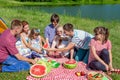 Outdoor group portrait of happy family having picnic near the lake and enjoying watermelon Royalty Free Stock Photo