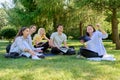 Outdoor, group of students with female teacher sitting on grass Royalty Free Stock Photo