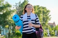 Outdoor happy mature woman walking after fit exercises in park, with backpack, yoga mat Royalty Free Stock Photo