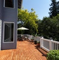 Outdoor home wooden deck during lovely summer day with seasonal garden Royalty Free Stock Photo