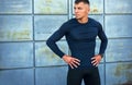 Outdoor image of a athletic man taking a break after workout in the city street. Sporty man in sportswear with hands on the waist