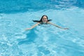 Outdoor image of cheerful adorable young lady enjoying active pasttime, fond of leisure activities, swimming in swimming pool Royalty Free Stock Photo