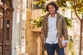 Outdoor image of handsome young man with books outdoors. College male student carrying books in college campus in autumn street Royalty Free Stock Photo