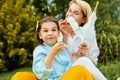 Outdoor image of happy mother eating cotton candy with her daughter sitting on the grass in the park. Mothers day. Royalty Free Stock Photo