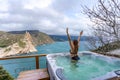 Outdoor jacuzzi with mountain and sea views. A woman in a black swimsuit is relaxing in the hotel pool, admiring the Royalty Free Stock Photo