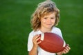 Outdoor kids sport activities. Kid boy having fun and playing american football on green grass park. Royalty Free Stock Photo