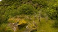 Outdoor landscape with a grassy hill with a large rock formation covered in moss Royalty Free Stock Photo