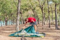 Outdoor lifestyle eco sport tourist put up set up green campsite, summer forest near lazur sea. Man assembling study