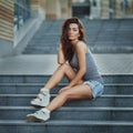 Outdoor lifestyle portrait of pretty young girl posing on stairway, wearing in hipster urban style on urban background Royalty Free Stock Photo