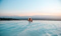 Outdoor luxury resort. Woman relaxing in nature swimming pool water. Sunset in the edge pool with beautiful view. Happy Royalty Free Stock Photo