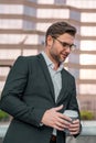 Outdoor male business portrait. Business man goals. Cheerful businessman in glasses with coffee to go by street towards Royalty Free Stock Photo