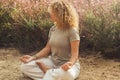 Outdoor meditation exercise for positive lifestyle and wellbeing. People enjoying yoga routine sitting on the ground near flowers.