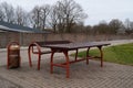 Outdoor metal dining table with bench and full waste bin in the city in autumn