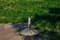 Outdoor metal post with concrete base on pavement and grass background Royalty Free Stock Photo