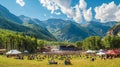 Outdoor music festival in a mountain valley with people and tents on a sunny day