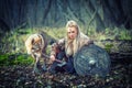 Outdoor northern warrior woman with braided hair and war makeup holding shield and ax with wolf next to her ready to attack -