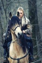 Outdoor northern warrior woman with braided hair and war makeup holding shield and ax with wolf next to her ready to attack - Royalty Free Stock Photo