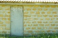 Outdoor old facade white closed door on ecological shells brick yellow wall background, copy space