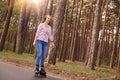Outdoor photo of attractive magnetic woman having positive facial expression, having roller skates on legs, listening to music, Royalty Free Stock Photo