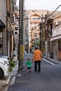 Outdoor photo of elderly man walking with young toddler on street in Kyoto, Japan.