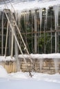 Outdoor photo of greenhouse in snowy winter botanical garden, icicles hanging from glasshouse roof Royalty Free Stock Photo