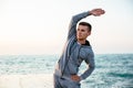 Handsome sportsman stretching on pier, near the sea Royalty Free Stock Photo
