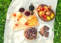 Outdoor picnic setting with red wine, cheese, fruits and cakes. Royalty Free Stock Photo