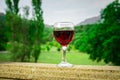 Outdoor picnic setting with wine or glass of wine on balcony with green field and mountains on background