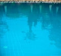 Outdoor pool. Palm trees and sun umbrellas are reflected in the water. Royalty Free Stock Photo