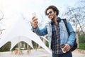 Outdoor portarit of happy sincere african american man in stylish glasses and denim coat, holding cup of coffee and Royalty Free Stock Photo