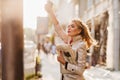 Outdoor portrait of active business-woman in trendy attire waiting for taxi in morning. Adorable fair-haired girl