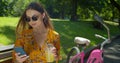 Outdoor portrait of attractive young woman on a bicycle used smartphone and drinking lemonade on a park bench. Royalty Free Stock Photo