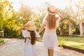 Outdoor portrait from back of tanned woman in white dress and her daughter in similar outfit enjoying lovely nature Royalty Free Stock Photo