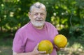 Portrait of a bearded senior taking two yellow melons in the hands