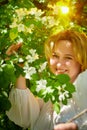 Outdoor portrait of a beautiful blonde middle-aged woman near blossom apple trees with white flowers Royalty Free Stock Photo