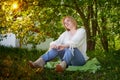 Outdoor portrait of a beautiful blonde middle-aged woman near blossom apple trees with white flowers Royalty Free Stock Photo