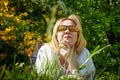 Outdoor portrait of a beautiful blonde middle-aged woman near blossom apple trees with white flowers Royalty Free Stock Photo