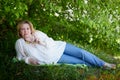 Outdoor portrait of a beautiful blonde middle-aged woman near blossom apple trees with white flowers Royalty Free Stock Photo