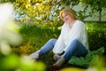 Outdoor portrait of a beautiful blonde middle-aged woman near blossom apple trees with white flowers Royalty Free Stock Photo