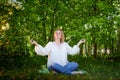 Outdoor portrait of a beautiful blonde middle-aged woman near blossom apple trees with white flowers Royalty Free Stock Photo