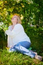 Outdoor portrait of a beautiful blonde middle-aged woman near blossom apple trees with white flowers Royalty Free Stock Photo