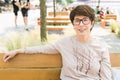 Outdoor portrait of beautiful and elegant middle age 55 - 60 year old woman wearing long sleeve top sitting on bench on Royalty Free Stock Photo