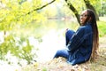 Outdoor portrait of beautiful happy laughing mixed race African American girl teenager female young woman sitting in the park near Royalty Free Stock Photo