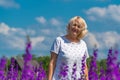 Outdoor portrait of a beautiful happy middle aged blonde woman in a field with flowers Royalty Free Stock Photo