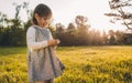 Outdoor portrait of beautiful little girl child playing with dandelion on meadow on sunset light. Cute child enjoy and explore Royalty Free Stock Photo