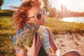 Outdoor portrait of beautiful young woman with red curly hair holding bouquet of flowers. Allergy free Royalty Free Stock Photo